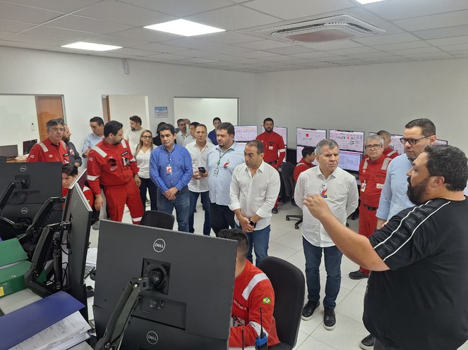 Foto mostra grupo de pessoas recebendo uma explicação de um homem com blusa preta