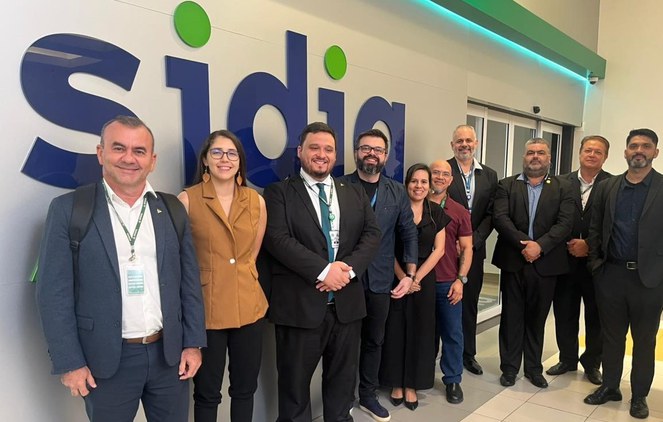 Foto mostra pessoas posando para foto em frente a um letreiro