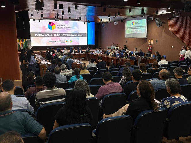 Foto mostra auditório lotado numa reunião e telão ao fundo