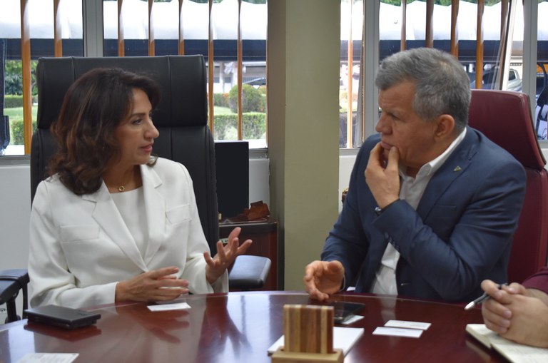 Foto mostra mulher de blazer branco fazendo uma explicação a um homem