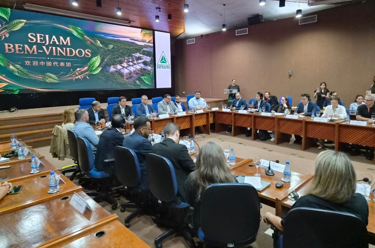 Foto mostra pessoas reunidas num auditório, com o apoio de um telão