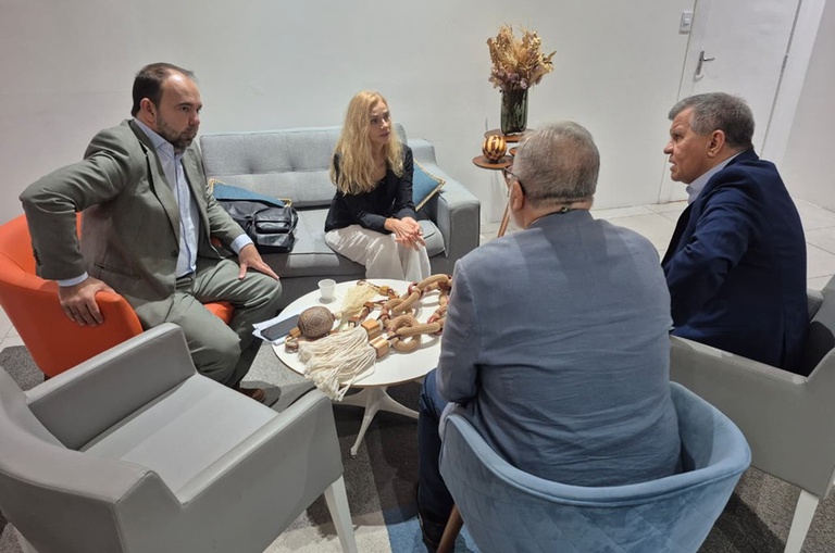 Foto mostra pessoas sentadas em uma reunião