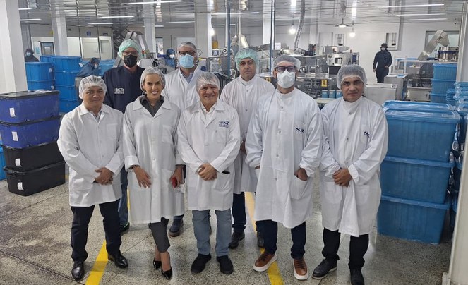 Foto mostra grupo de pessoas posando para foto, vestidas de jaleco e touca