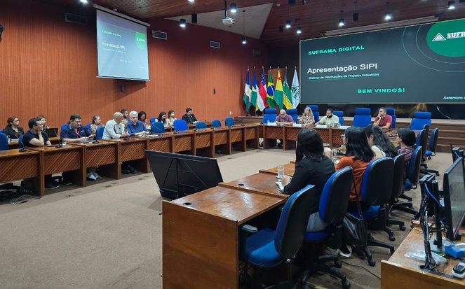 Foto mostra pessoas reunidas em um auditório e um telão ao fundo
