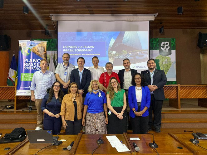 Foto mostra grupo de pessoas e um telão ao fundo