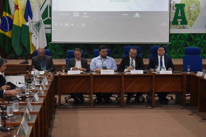 Foto mostra grupo de pessoas reunidas num auditório e um telão ao fundo como apoio