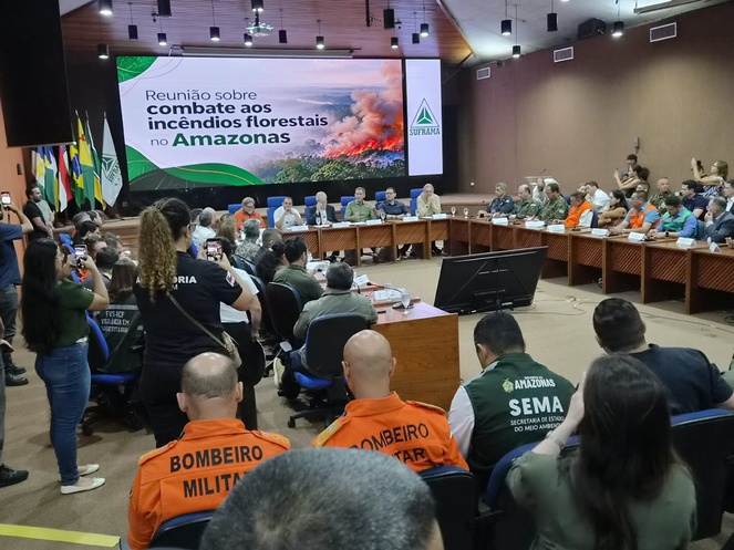 Foto mostra grupo de pessoas reunidas num auditório com um telão como apoio