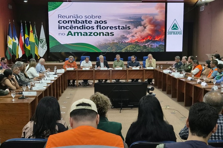 Foto mostra evento em um auditório com um telão ao fundo