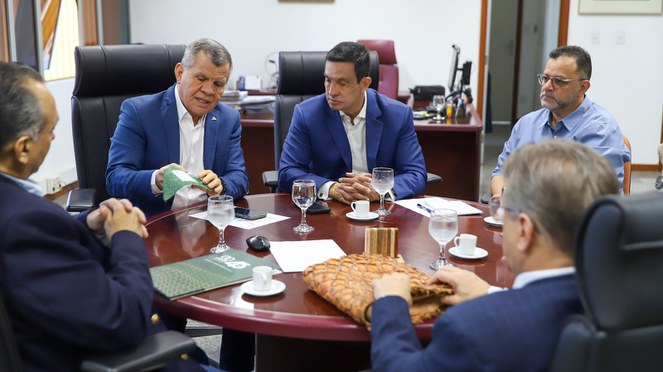 Foto mostra homem mostrando folheto verde a outros homens