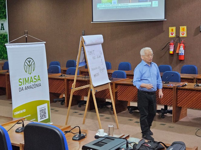 Foto mostra homem em pé de blusa azul ministrando uma palestra