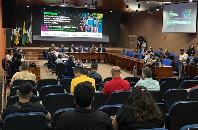 Foto mostra evento em auditório, com um telão de fundo