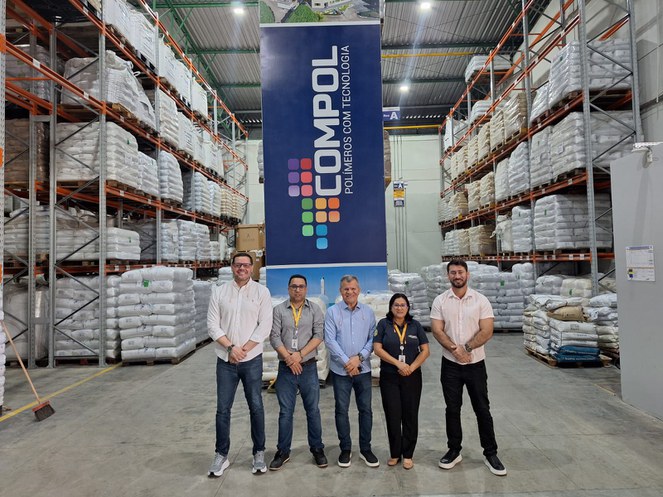 Foto mostra pessoas posando para foto com vários sacos brancos ao fundo