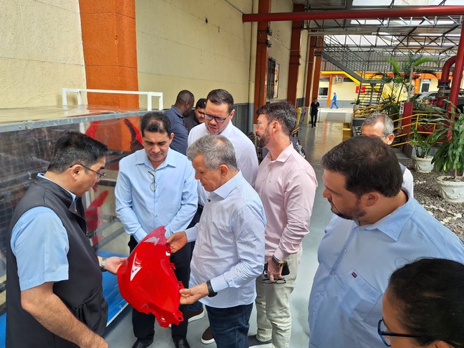 Foto mostra homem segurando uma peça vermelha