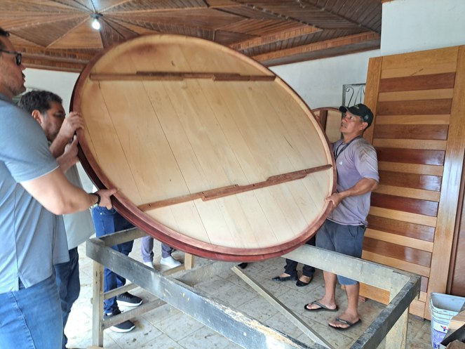 Foto mostra homens mexendo numa mesa redonda