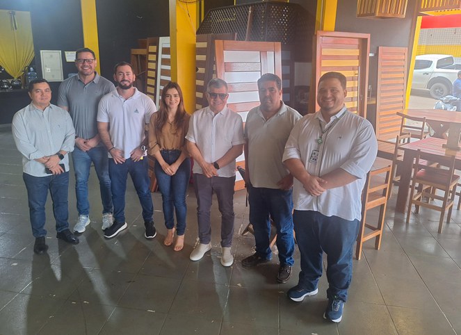 Foto mostra grupo de pessoas posando para fotografia em uma loja de móveis