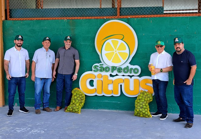 Foto mostra homens ao lado de sacos com laranjas