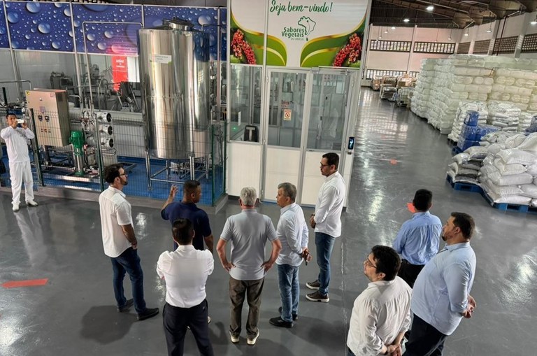 Foto mostra pessoas reunidas dentro de uma fábrica