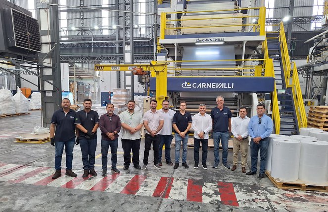 Foto mostra homens posando para foto numa fábrica de plásticos