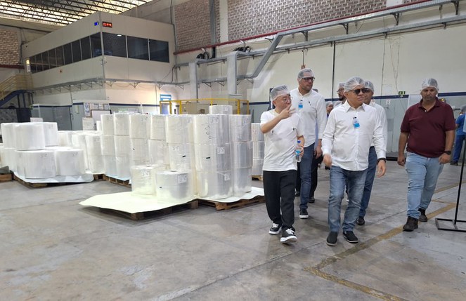 Foto mostra homens com touca cabeça e produtos plásticos ao redor