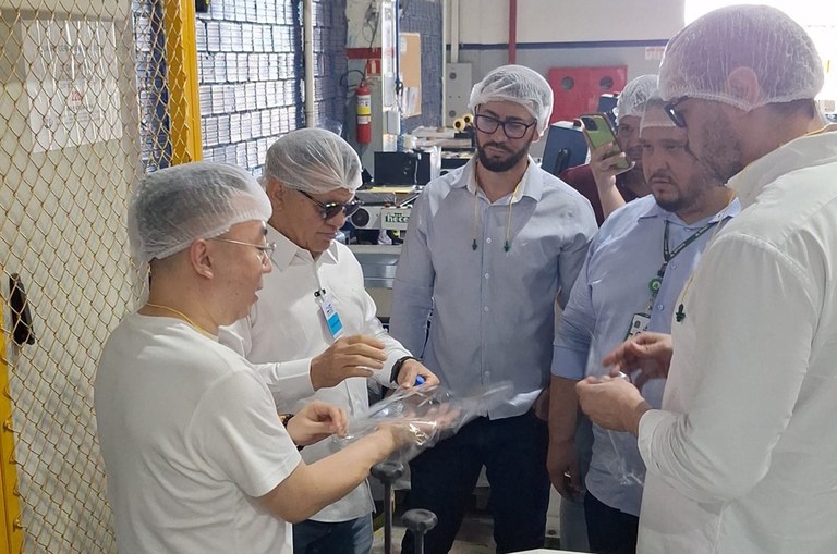 Foto mostra homens de touca na cabeça observando um objeto plástico