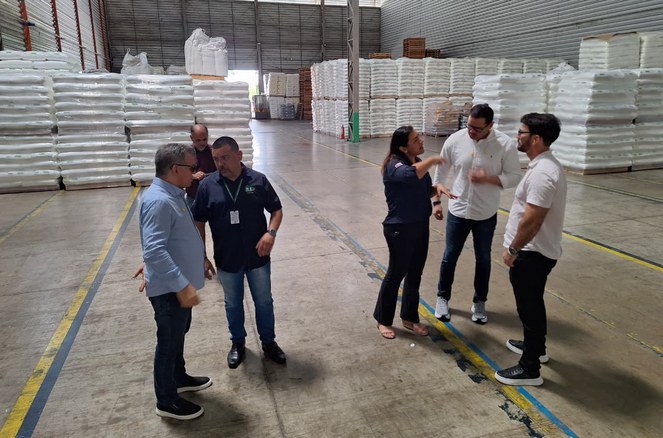 Foto mostra grupo de pessoas e sacos brancos