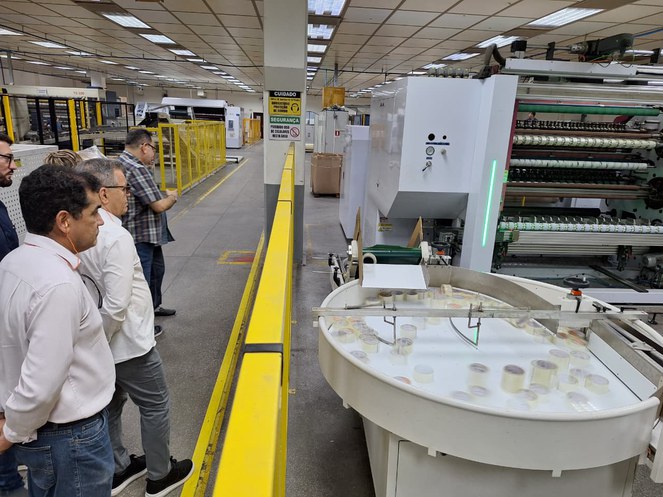 Foto mostra homens olhando para um recipiente cheio de fitas adesivas