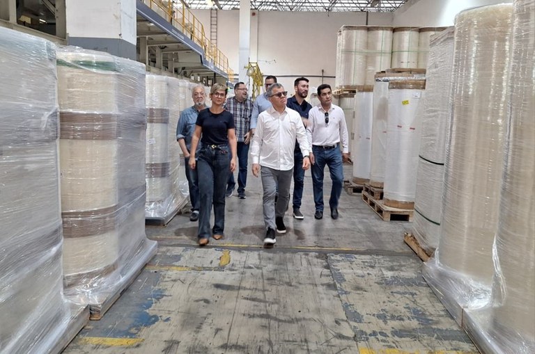 Foto mostra grupo de pessoas caminhando com tubos de plásticos ao redor