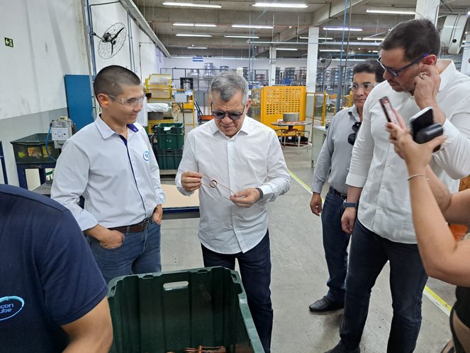 Foto mostra homem de camisa branca com um objeto na mão