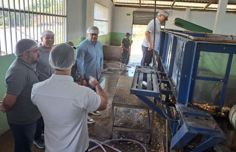 Foto mostra homem de touca em cima de um suporte olhando para dentro de uma máquina em funcionamento