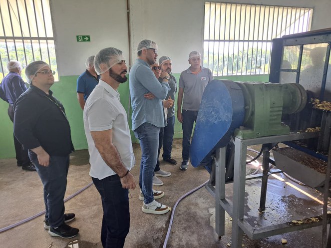 Foto mostra homens de touca olhando para uma máquina em funcionamento