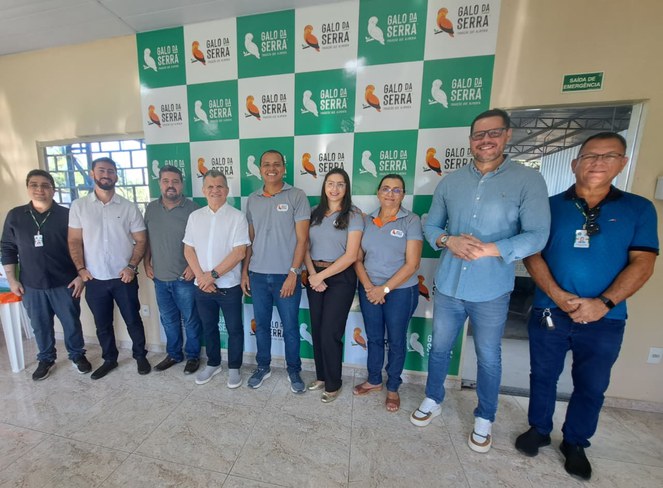Foto mostra grupo de pessoas posando para fotografia com um painel grande ao fundo