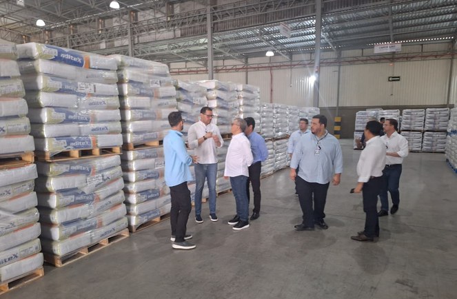 Foto mostra grupo de pessoas reunidas ao lado de sacos brancos