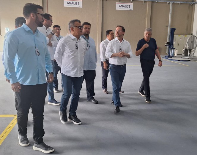 Foto mostra grupo de pessoas caminhando dentro de fábrica