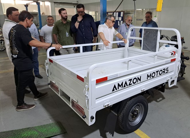 Foto mostra homens observando um triciclo utilitário