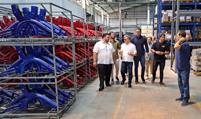 Foto mostra grupo de homens caminhando próximas a peças de motocicletas