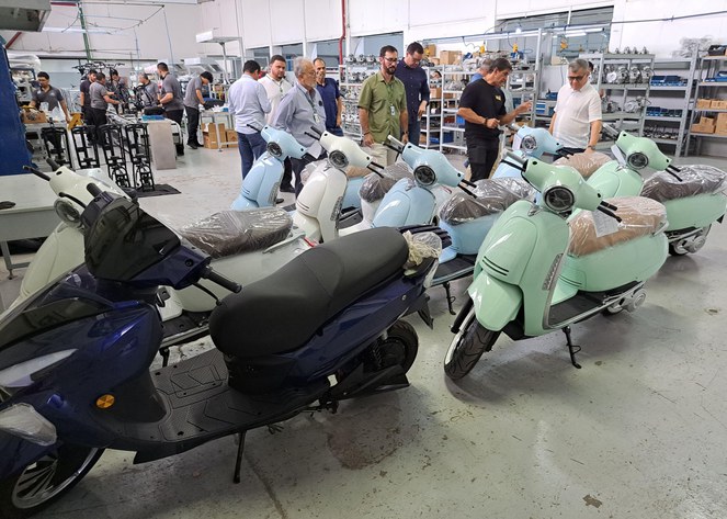 Foto mostra motos agrupadas e um grupo de homens conversando sobre os veículos