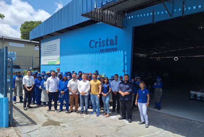 Foto mostra grupo de pessoas posando para foto em frente a um empresa de fachada na cor azul