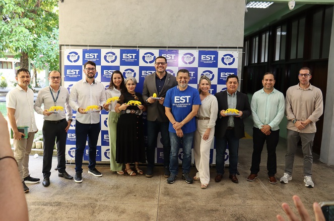 Foto mostra pessos posando para foto com objeto amarelo nas mãos