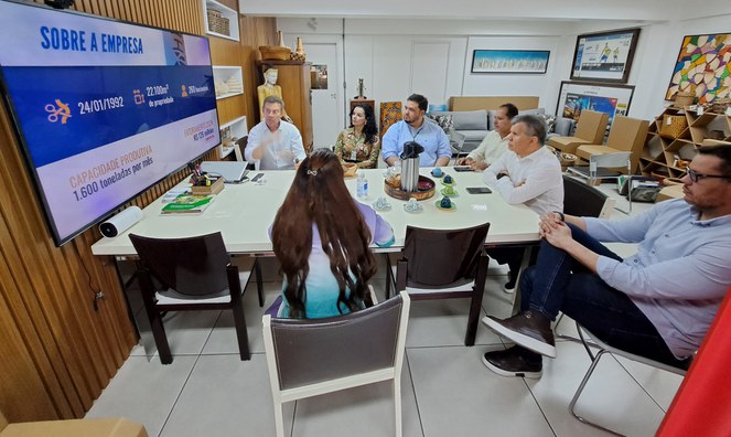 Foto mostra homem de blusa branca fazendo uma explicação, com um telão como apoio