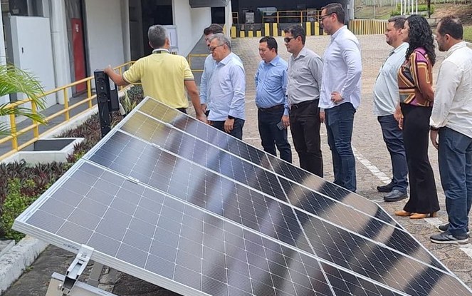 Foto mostra pessoas olhando para equipamento de energia