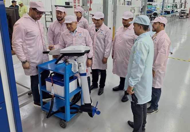 Foto mostra pessoas de bata olhando para equipamento