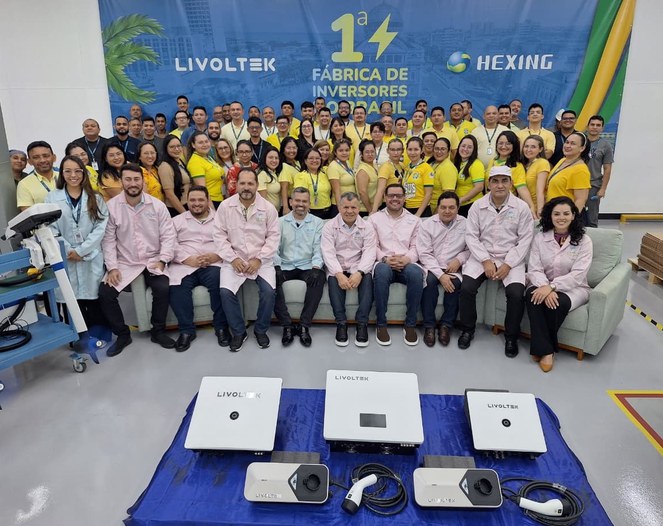 Foto mostra pessoas posando para sessão de fotos, em frente a uns equipamentos