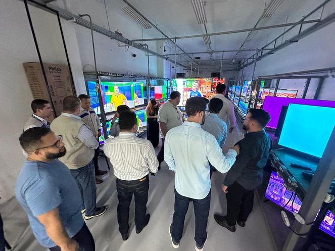 Foto mostra pessoas verificando uma exposição de produtos eletroeletrônicos