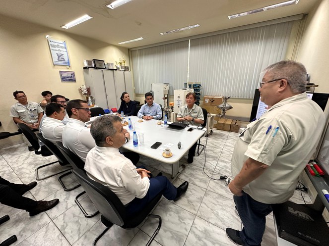 Foto mostra homem em pé de óculos fazendo uma explanação a um grupo de pessoas