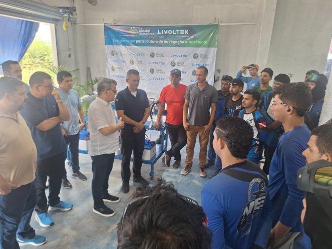 Foto mostra homem de camisa branca conversando com grupo de pessoas