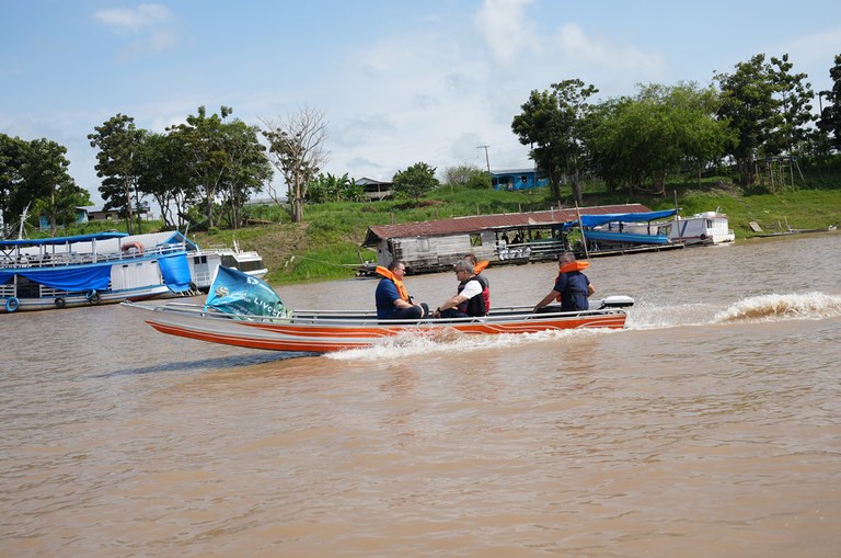 Foto mostra homens equipados de colete e num barco em movimento