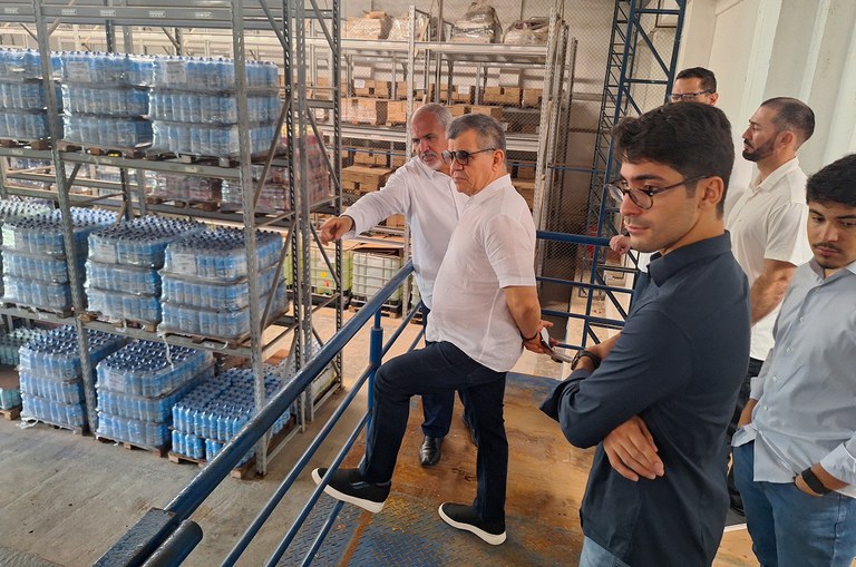 Foto mostra o superintendente da Suframa (camisa branca e óculos) e equipe conhecendo a linha de produção da empresa Topázio