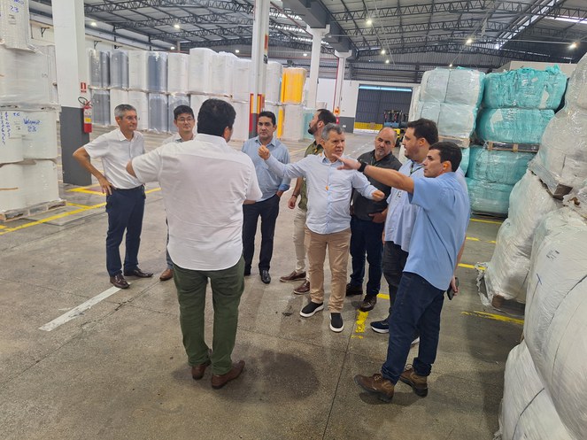 Foto mostra homens gesticulando, com várias sacas de material plástico ao fundo