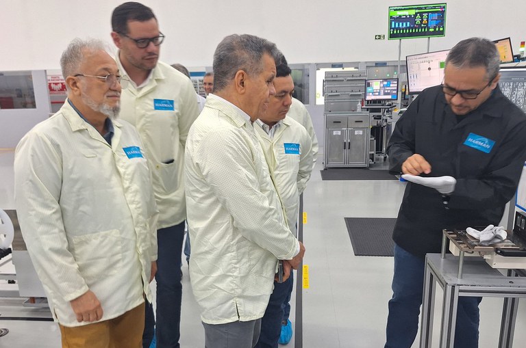 Foto mostra mostra objeto que está na mão dele a outros homens