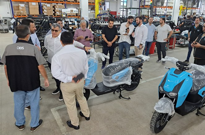 Foto mostra homens conversando, com um deles (de blusa branca), se apoiando em uma delas